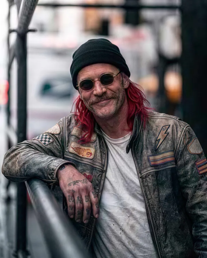 A pixelated street portrait of a biker is restored with crisp leather, tattoos and stubble.